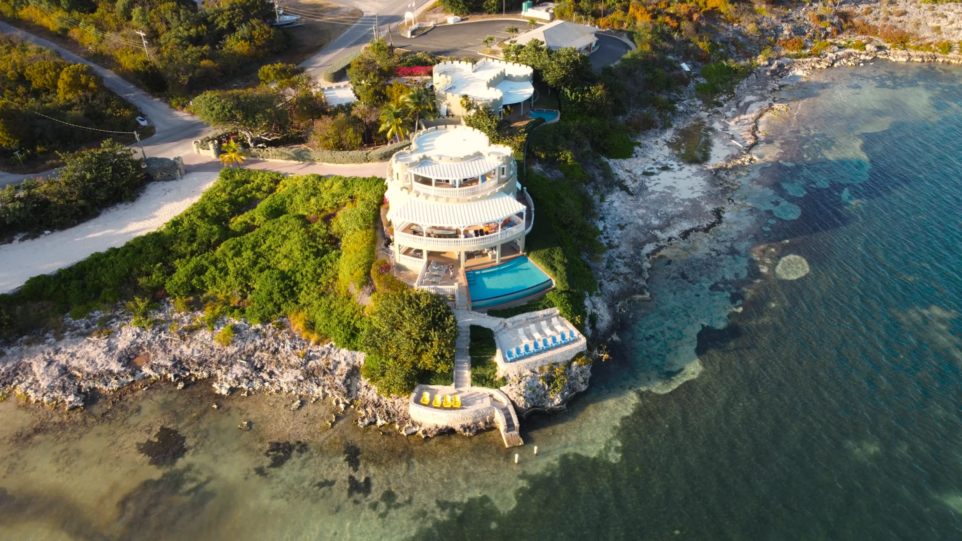 A white seafront villa and private pool on the rocky coastline of Grand Cayman